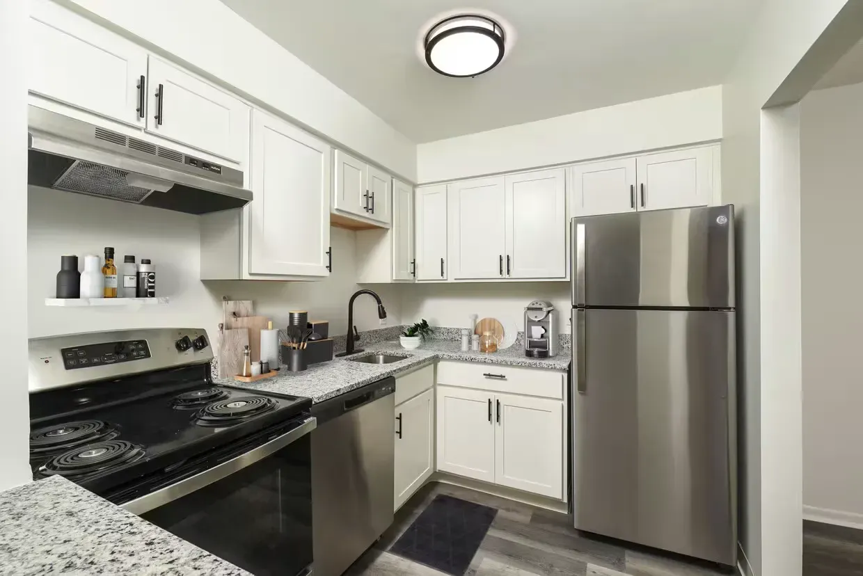 Bright white apartment kitchen with granite counters and stainless steel appliances at the Reserves at Arlington in Columbus, OH.