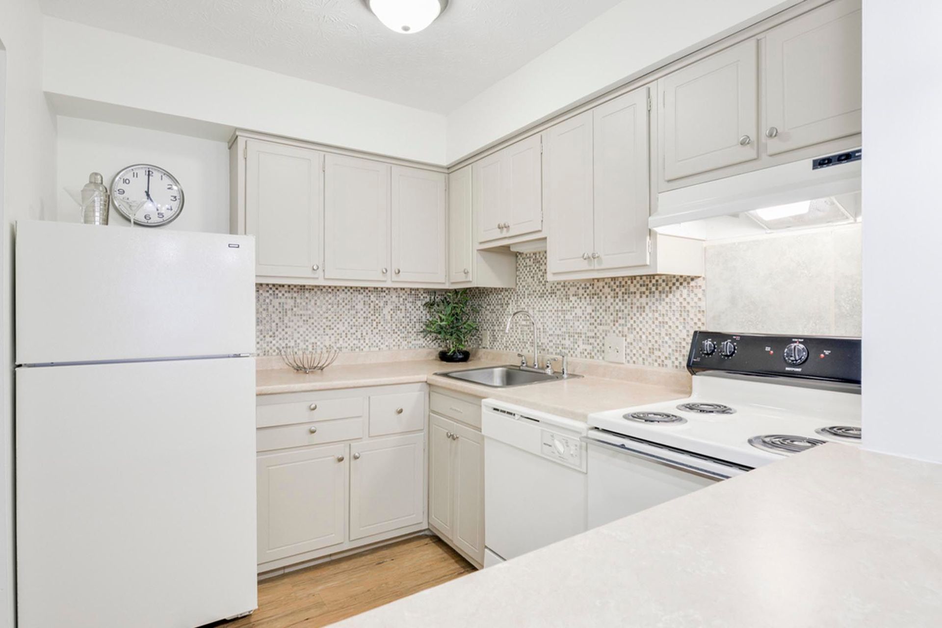 Kitchen in an apartment with white cabinets, fridge, dishwasher, stove, and a mosaic backsplash at the Reserves at Arlington in Columbus, OH.