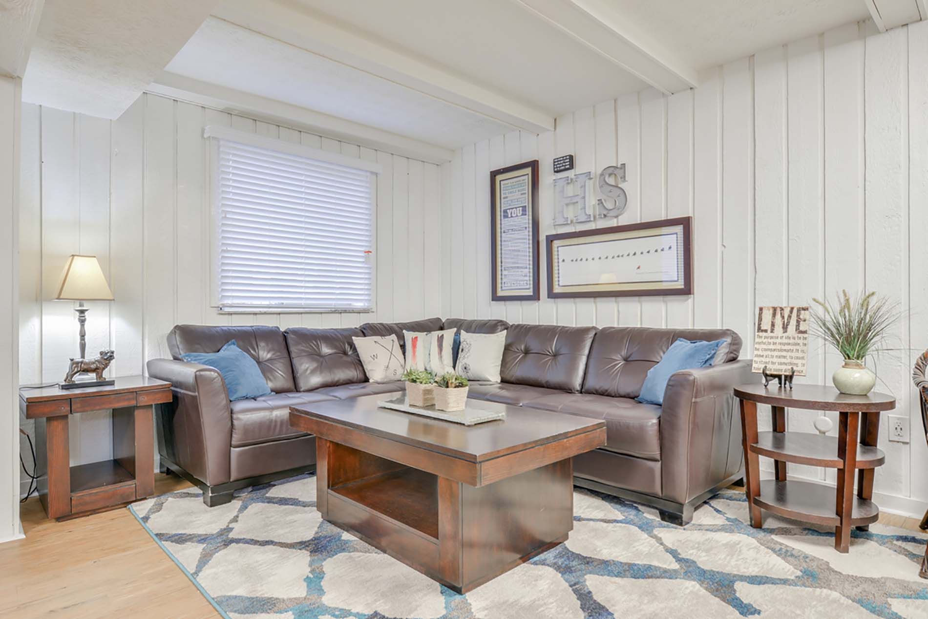 Cozy living room with a brown leather sectional, wooden coffee table, and matching side tables at the Reserves at Arlington in Columbus, OH.