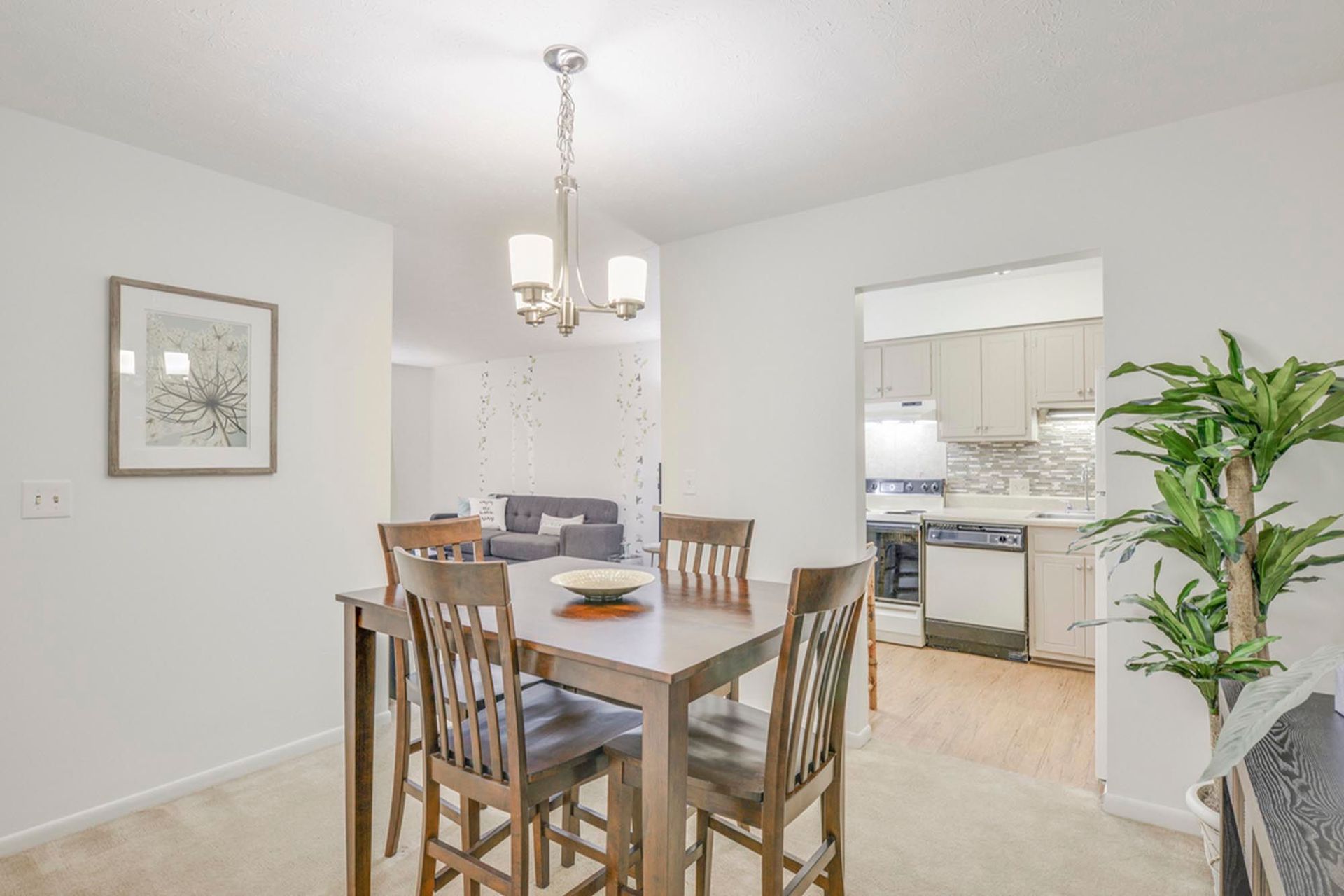 Open dining area with a wooden table and chairs, open to a modern kitchen at the Reserves at Arlington in Columbus, OH.