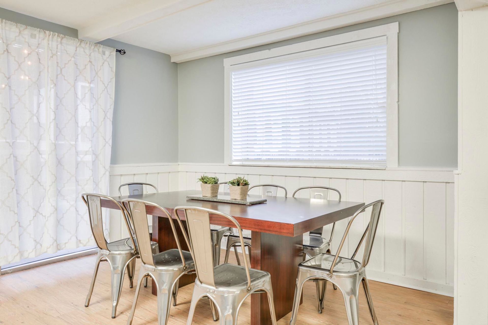 Dining area with a wooden table, metal chairs, light blue walls, and a window with blinds at the Reserves at Arlington in Columbus, OH.