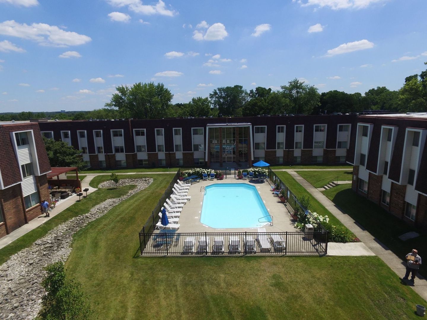 Aerial view of a central swimming pool surrounded by lounge chairs and brick apartment buildings at the Reserves at Arlington in Columbus, OH.