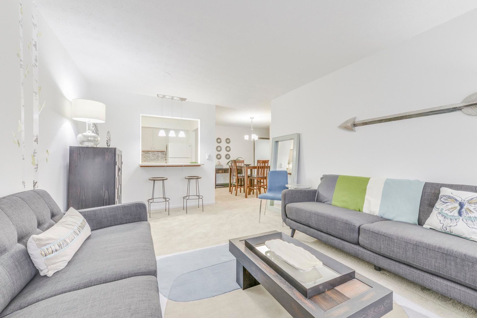 Living room in an apartment with two gray sofas and an open kitchen at the Reserves at Arlington in Columbus, OH.