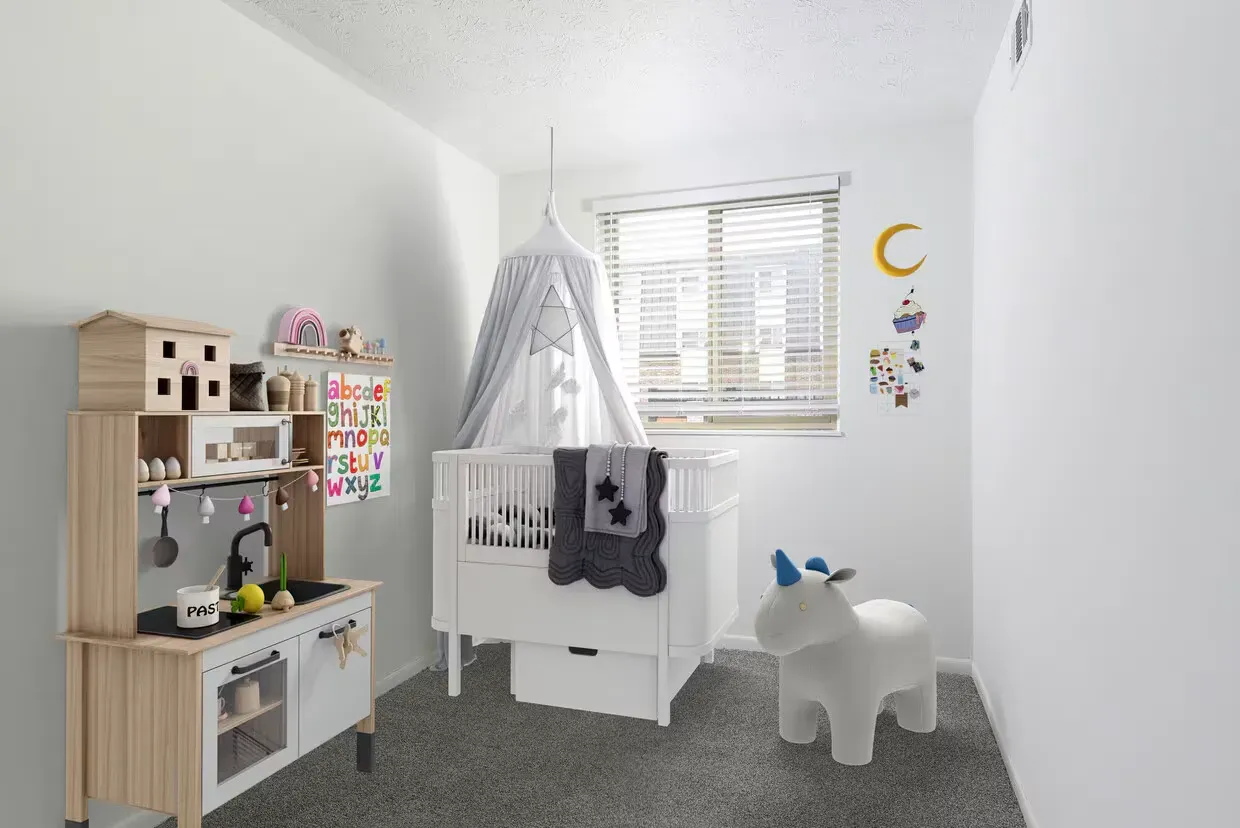 Bright nursery with white crib under a canopy, toy kitchen, and pastel decor by a window at the Reserves at Arlington in Columbus, OH.