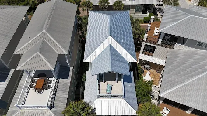 Aerial view of beach houses with metal roofs. One house has a porch with a blue chair.