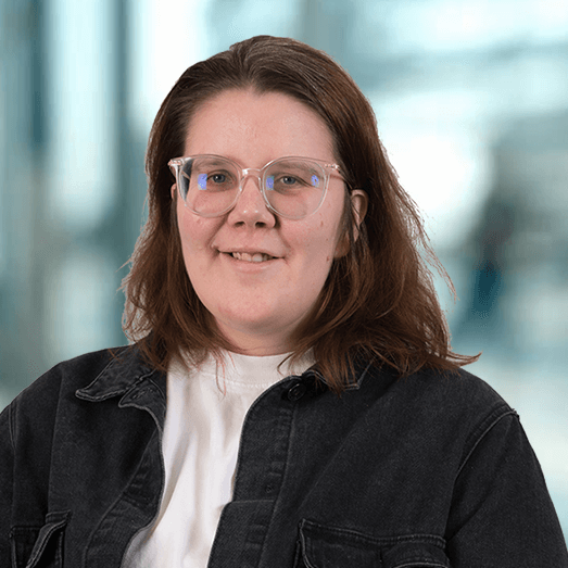 A woman wearing glasses and a black jacket is smiling for the camera.