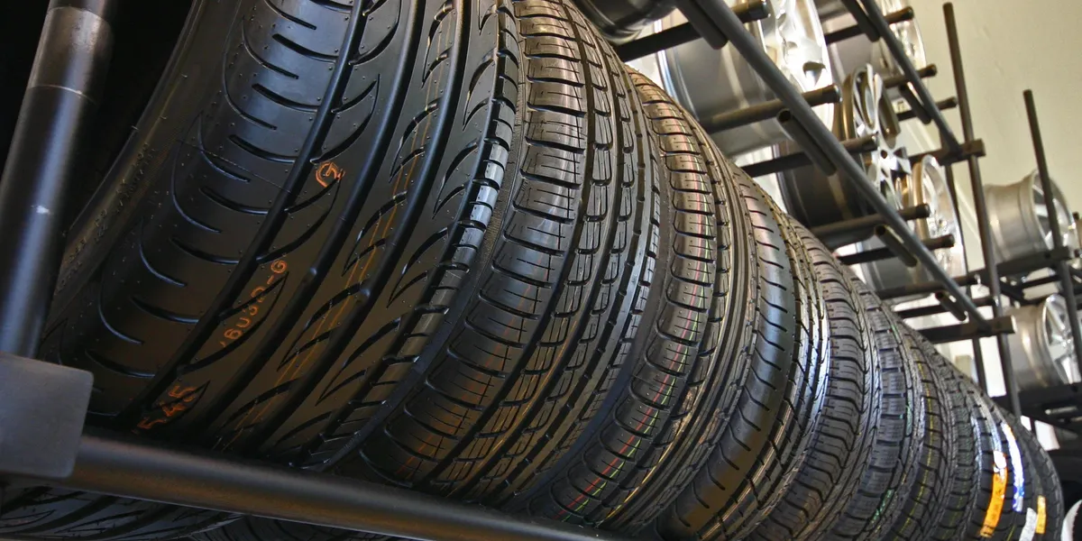 Row of tires stacked on a rack in a shop, angled perspective. | Equality Automotive