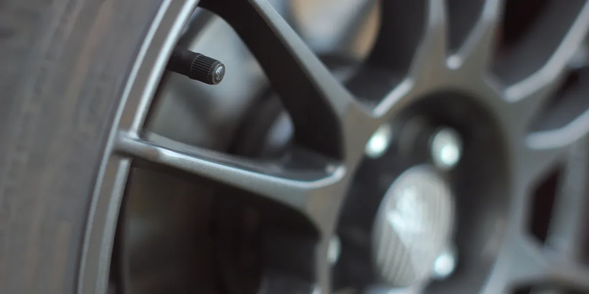 Close-up of a car wheel with a tire valve and gray spokes. | Equality Automotive