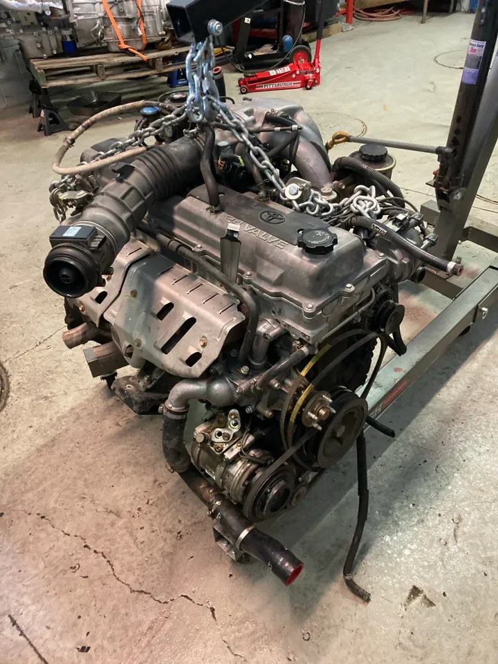 Engine block being lifted by chains in a workshop setting. | Equality Automotive