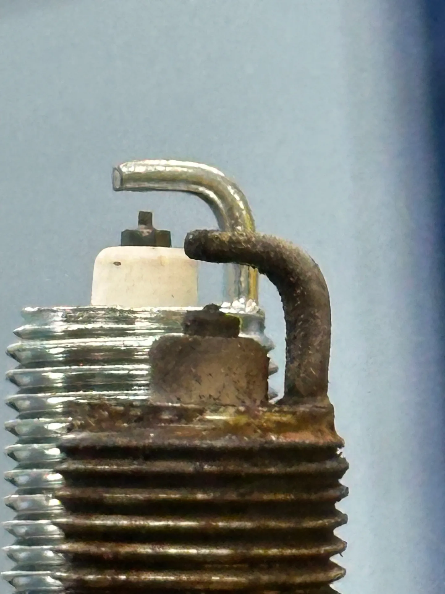 Close-up of a used spark plug, showing the electrode and threaded base with signs of wear and residue. | Equality Automotive