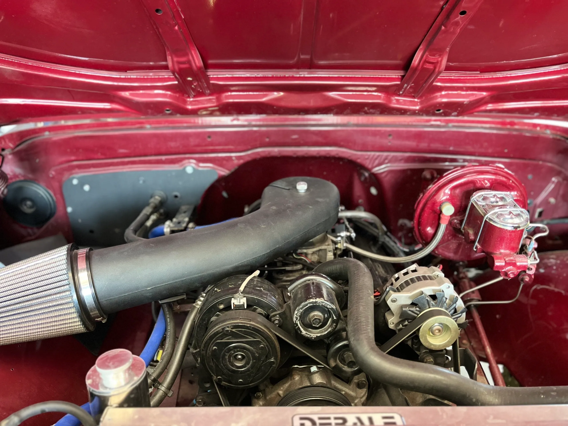 Red engine bay with a black engine and air intake; chrome brake master cylinder. | Equality Automotive