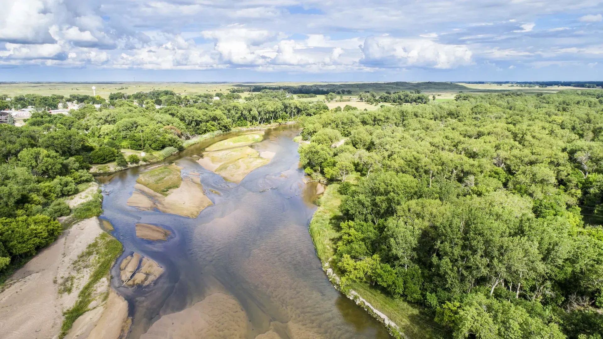 An aerial view of a river surrounded by trees on a cloudy day.
