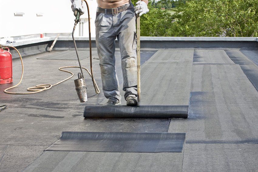 A roofer covering a roof with roofing felt