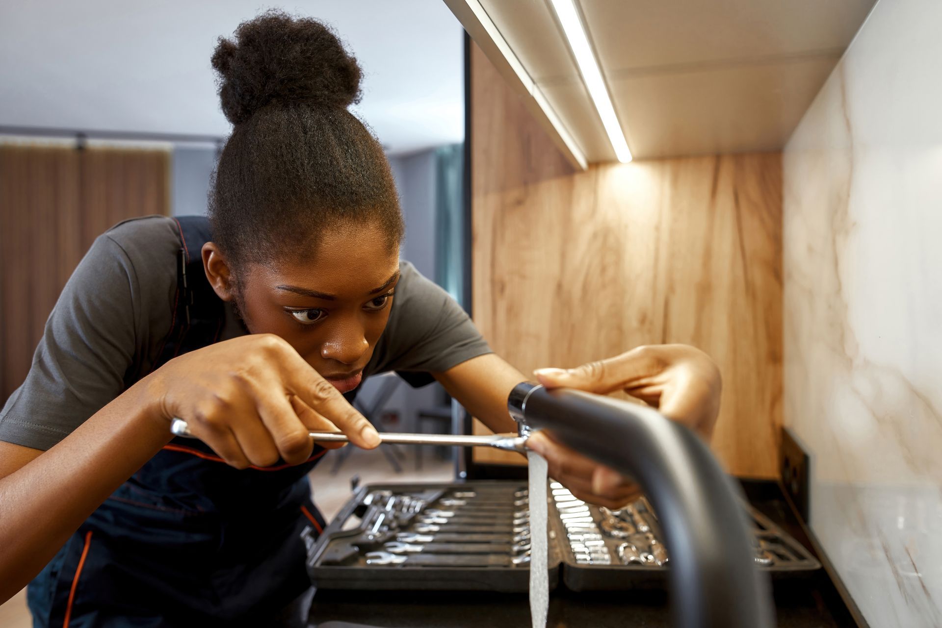 Competent young woman plumber repairing a plumbing fixture.