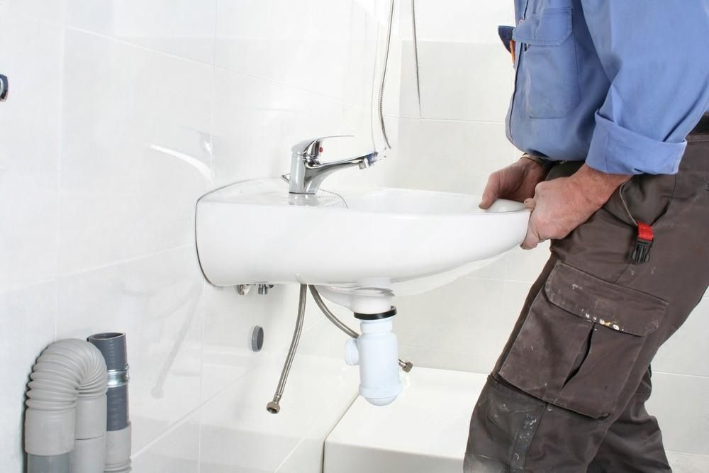 a person is fixing a shower head in a bathroom .