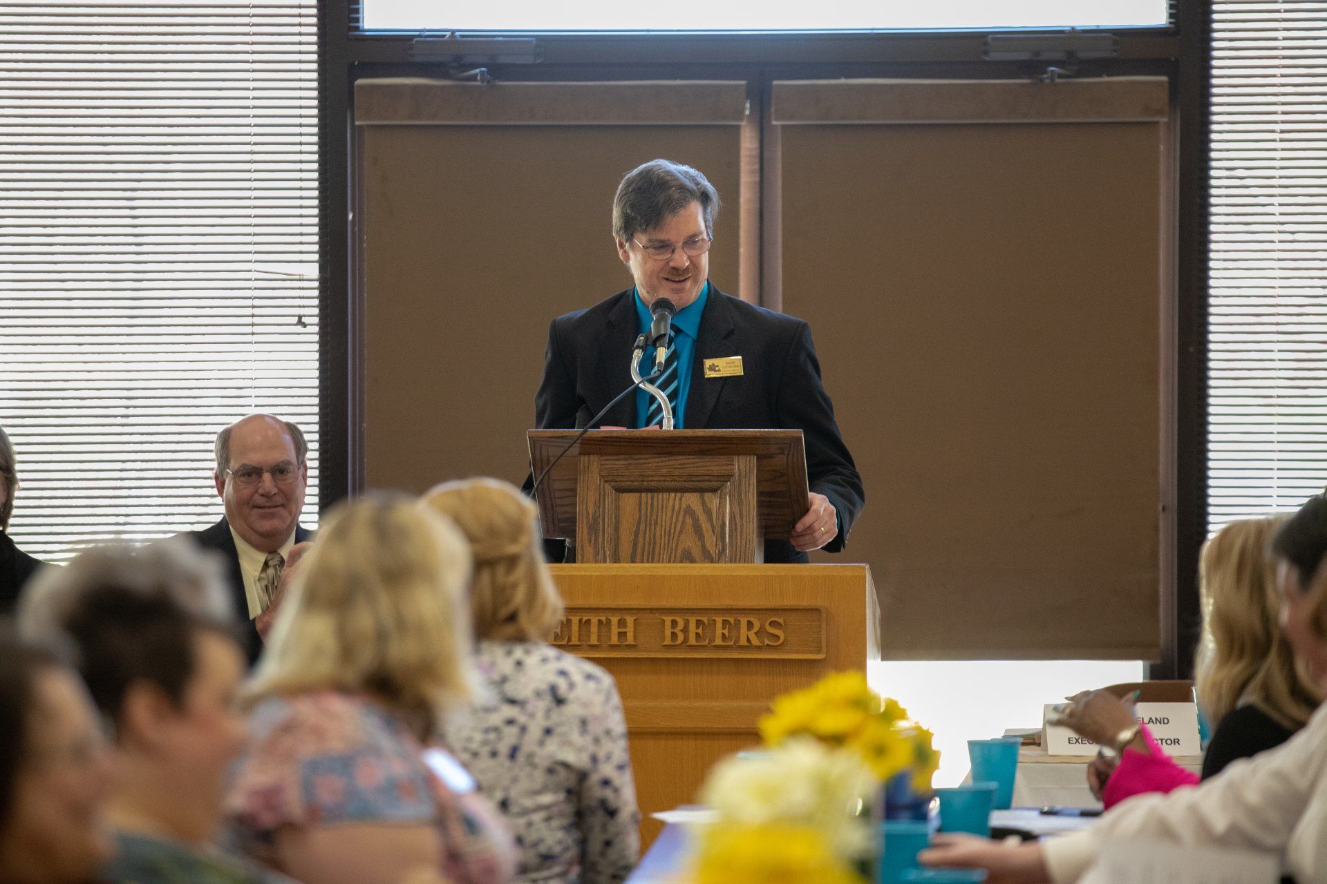 A man is standing at a podium giving a speech to a group of people.