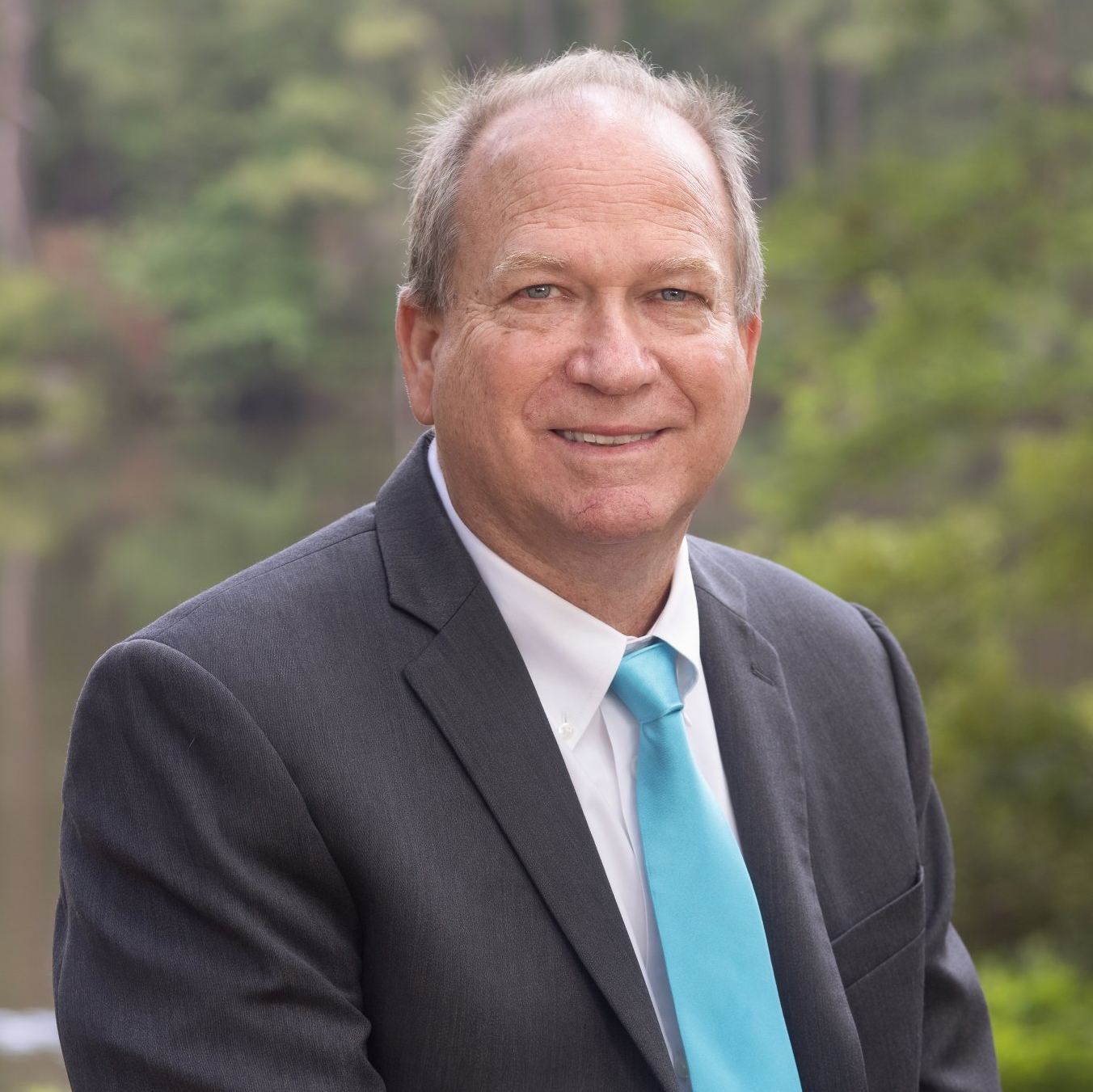 A man in a suit and tie is smiling for the camera.
