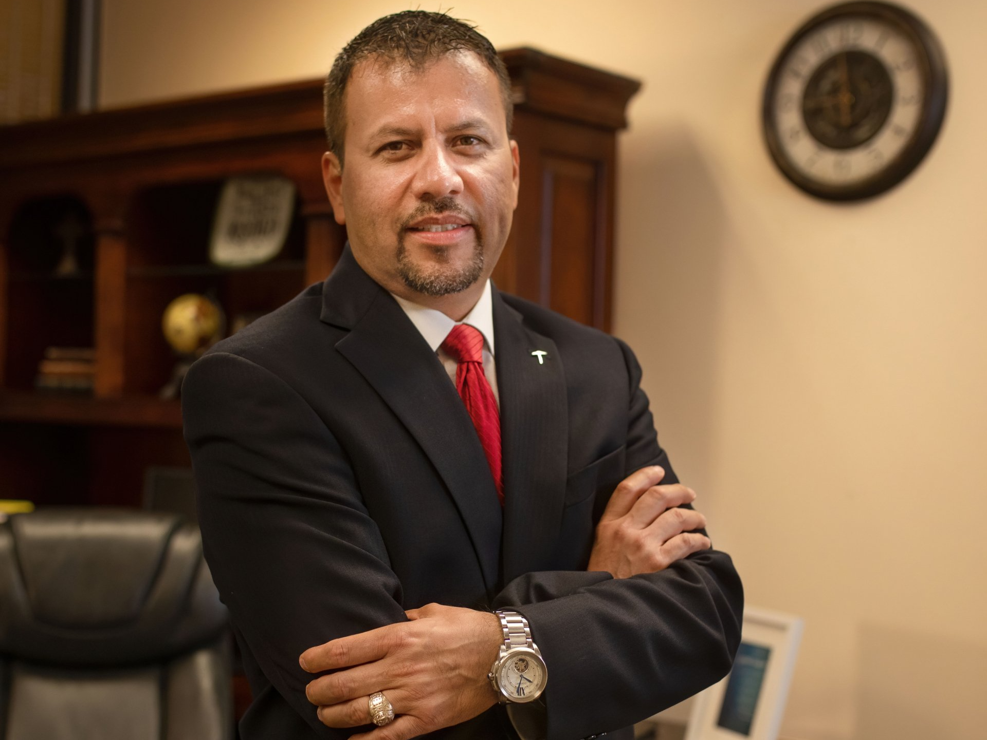 A man in a suit and tie is standing with his arms crossed.