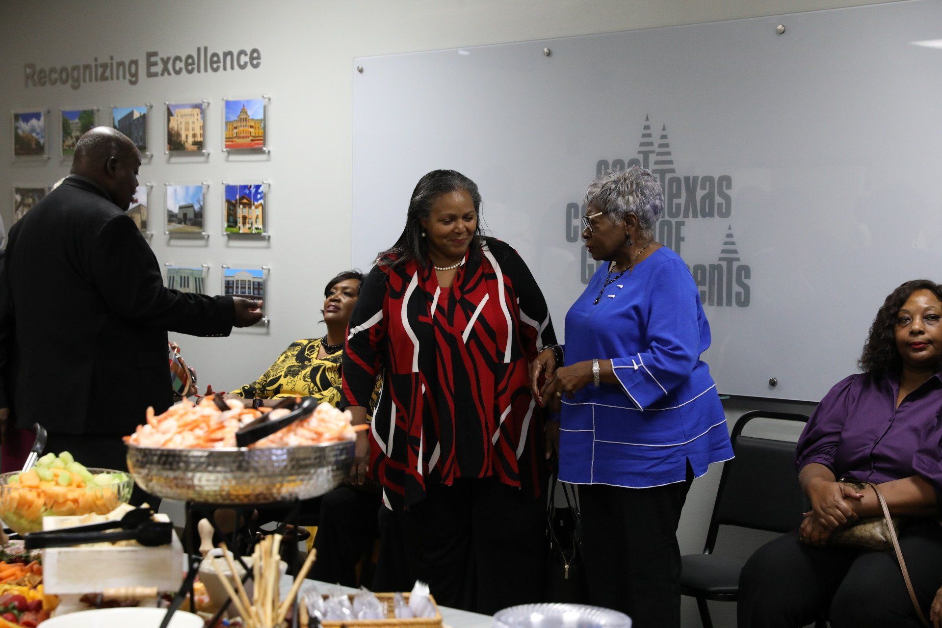 A group of people standing around a table with a sign that says recognizing excellence