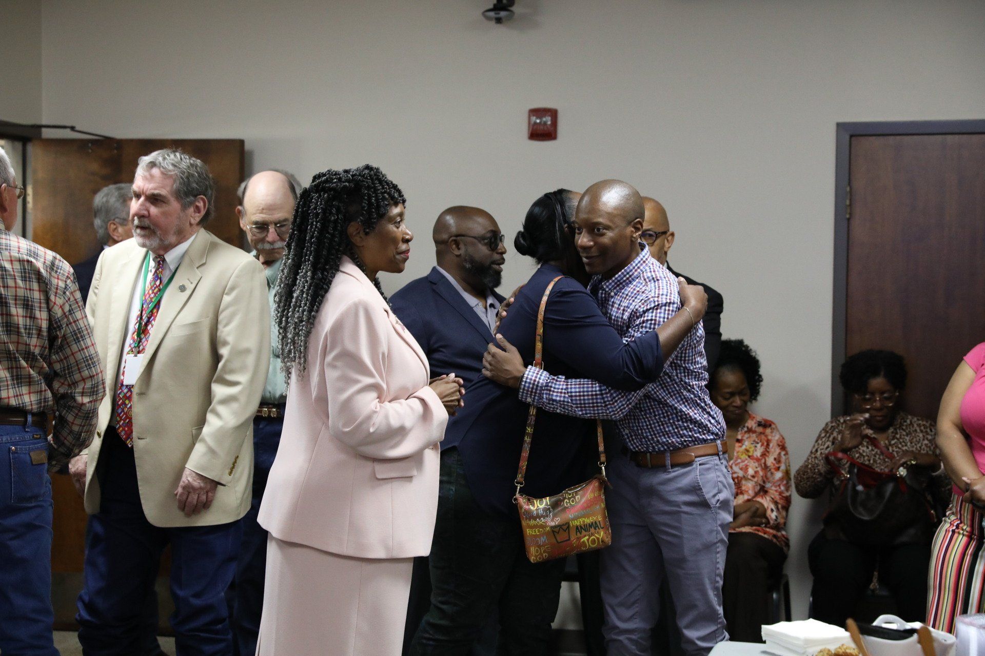 A group of people are hugging each other in a room.