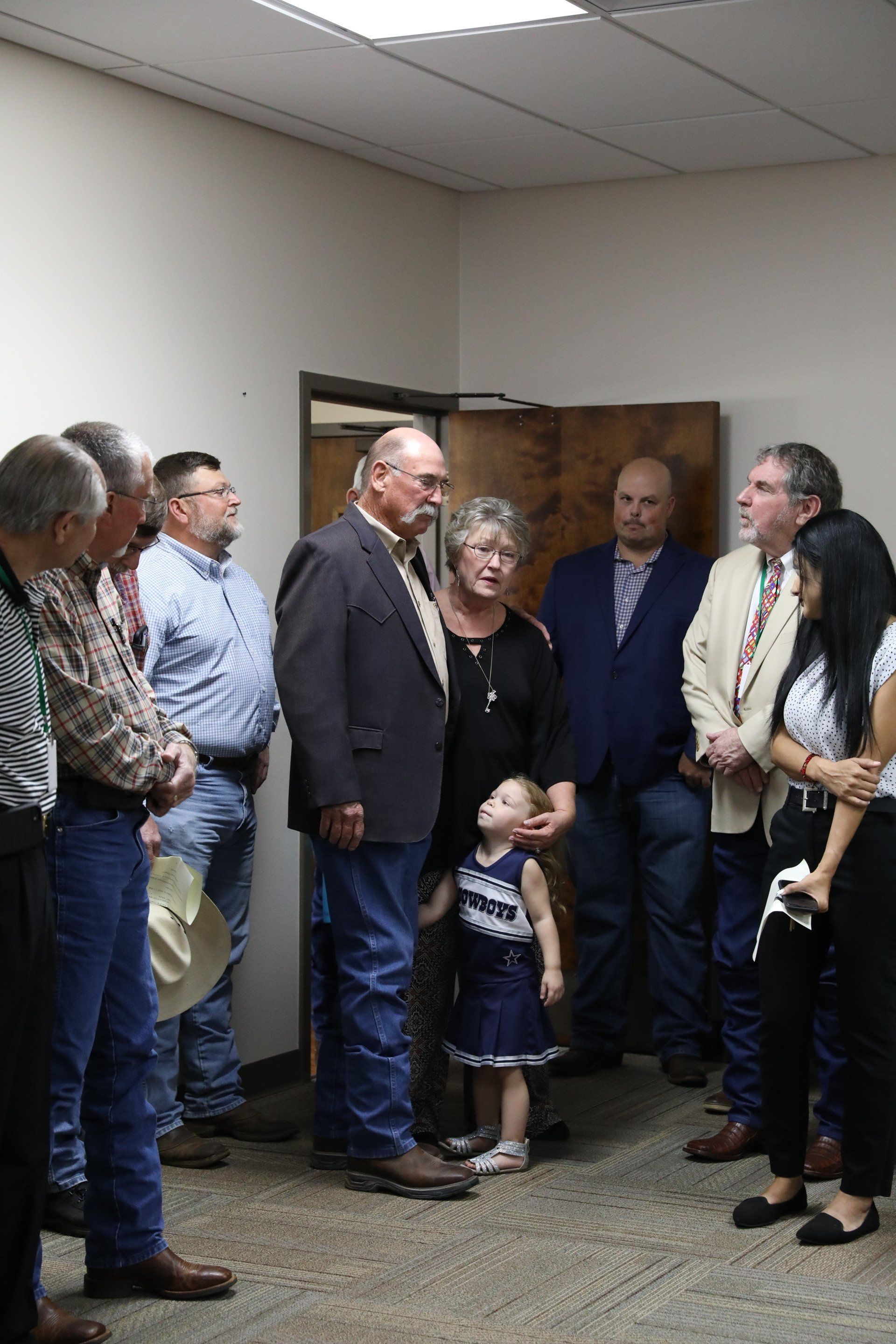 A group of people are standing in a room talking to each other.