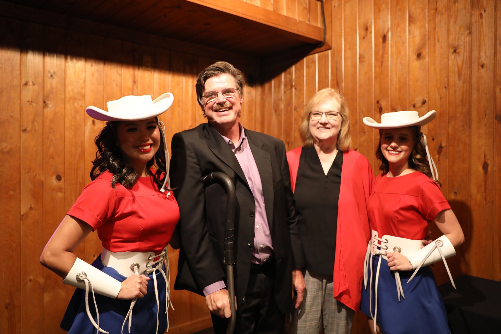 A man in a suit and two women in cowboy hats pose for a picture