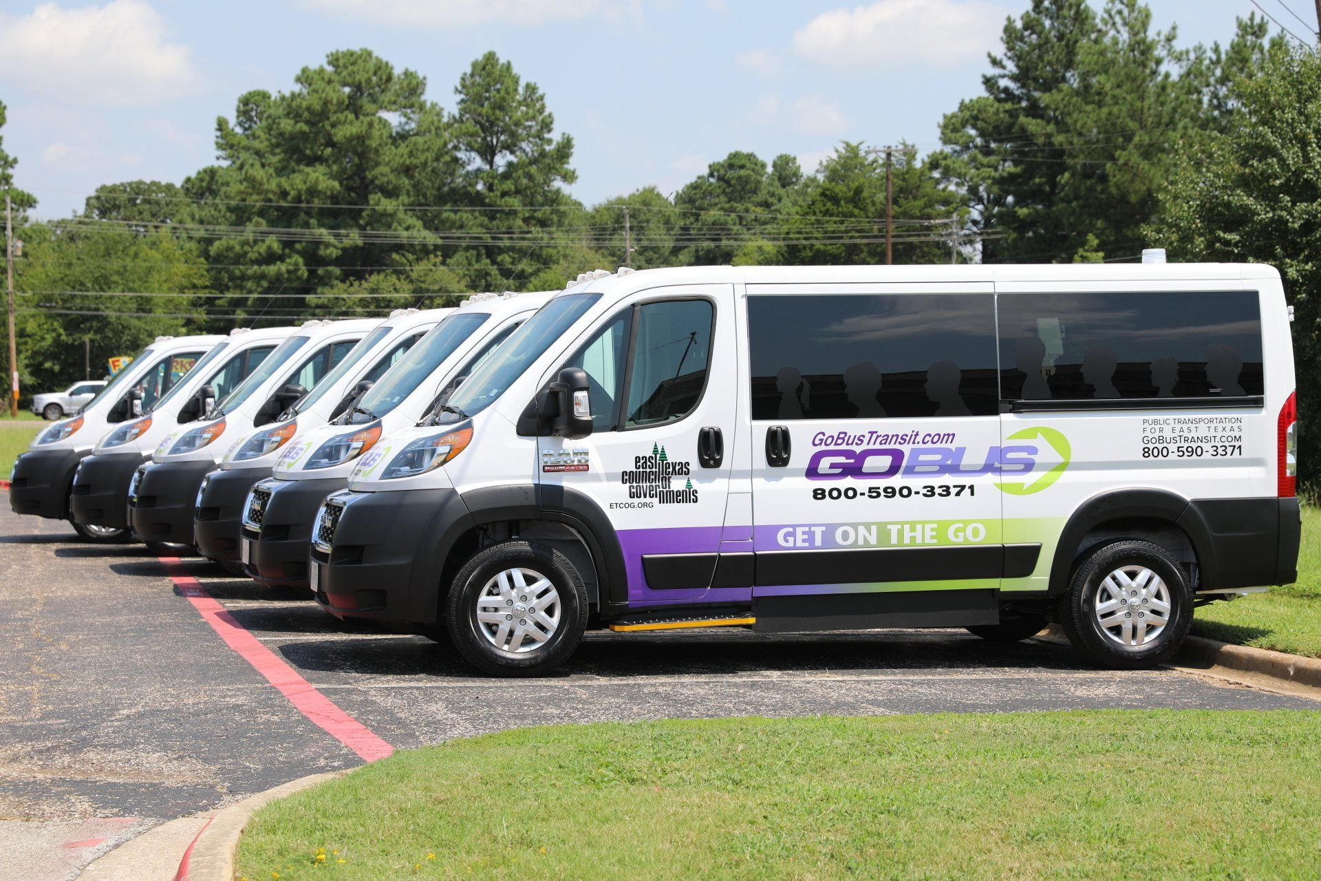 A row of vans are parked in a parking lot.