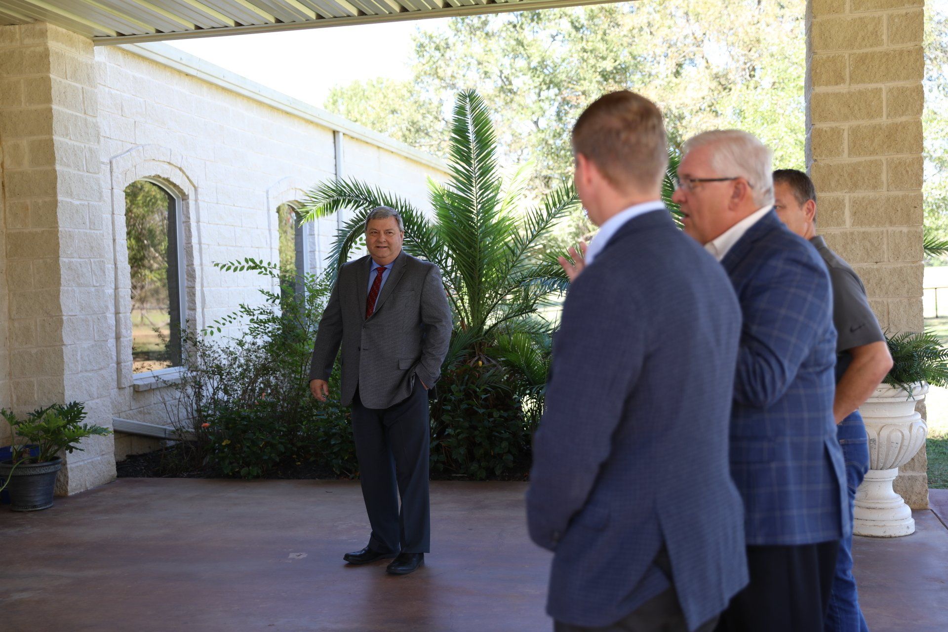 A group of men are standing outside of a building talking to each other.