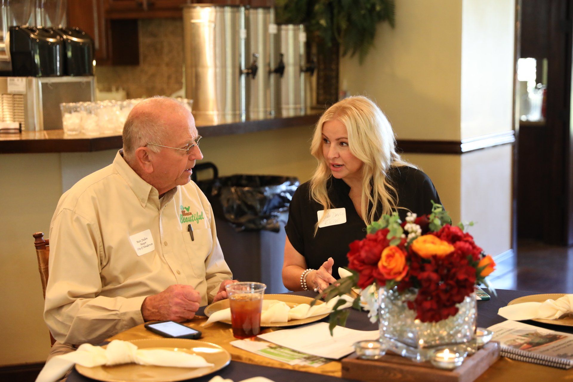 A man and a woman are sitting at a table talking to each other.