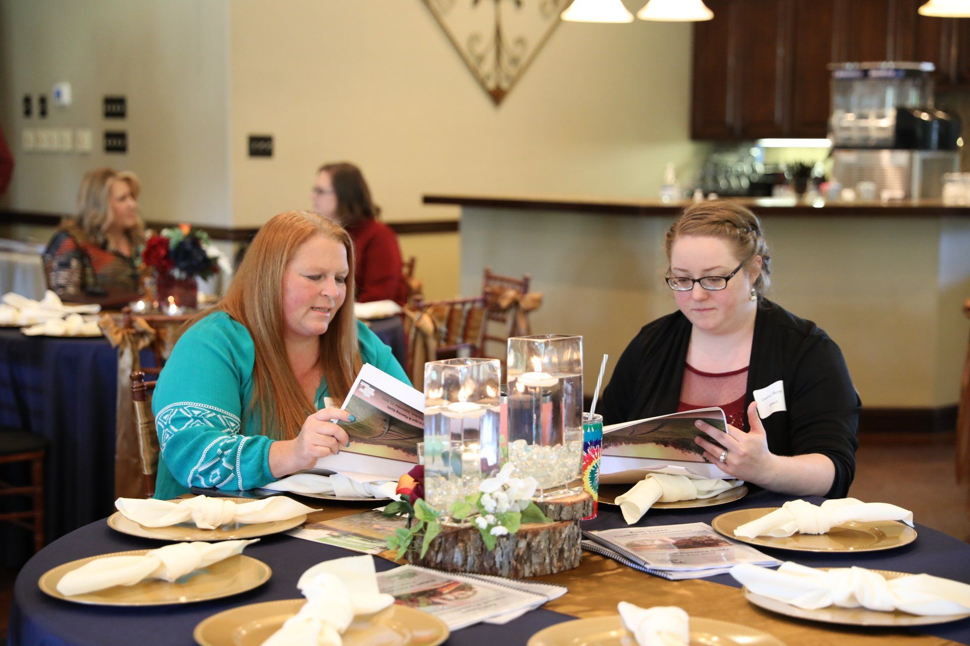 Two women are sitting at a table in a restaurant looking at a menu.