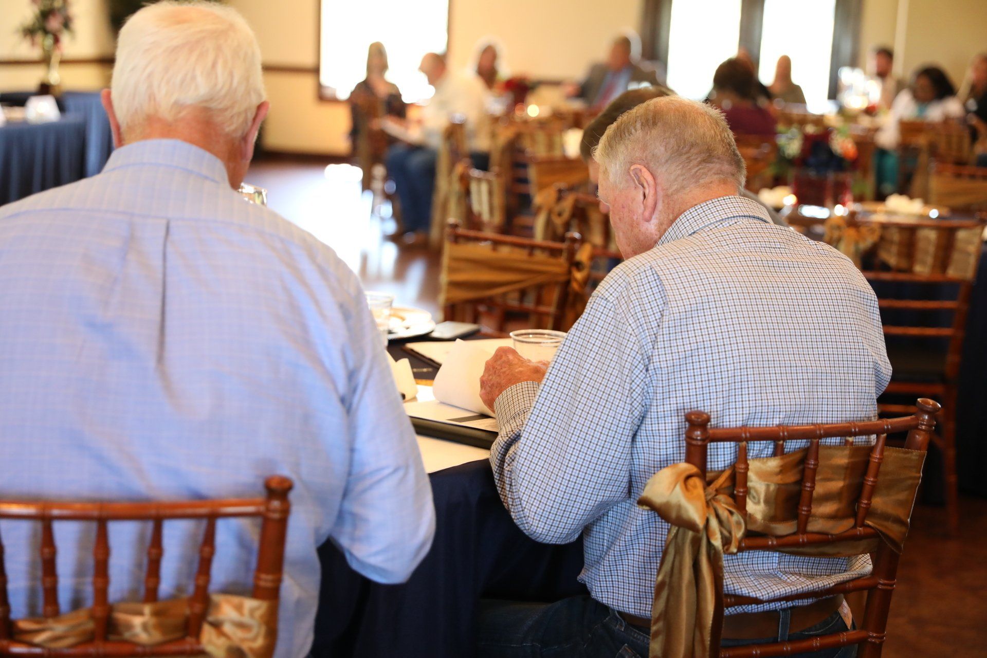 Two men are sitting at a table in a restaurant writing on a piece of paper.