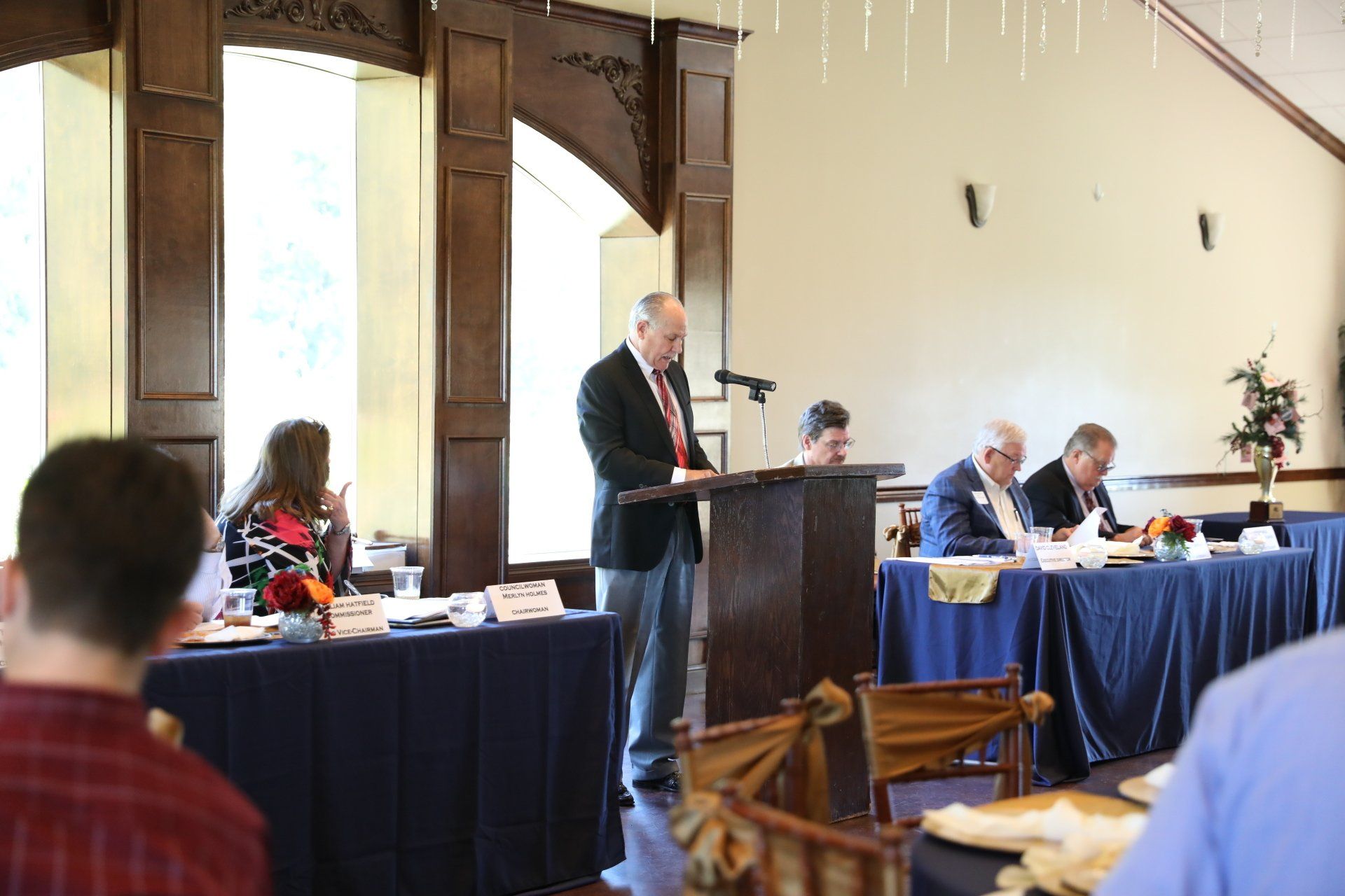 A man is standing at a podium giving a speech to a group of people