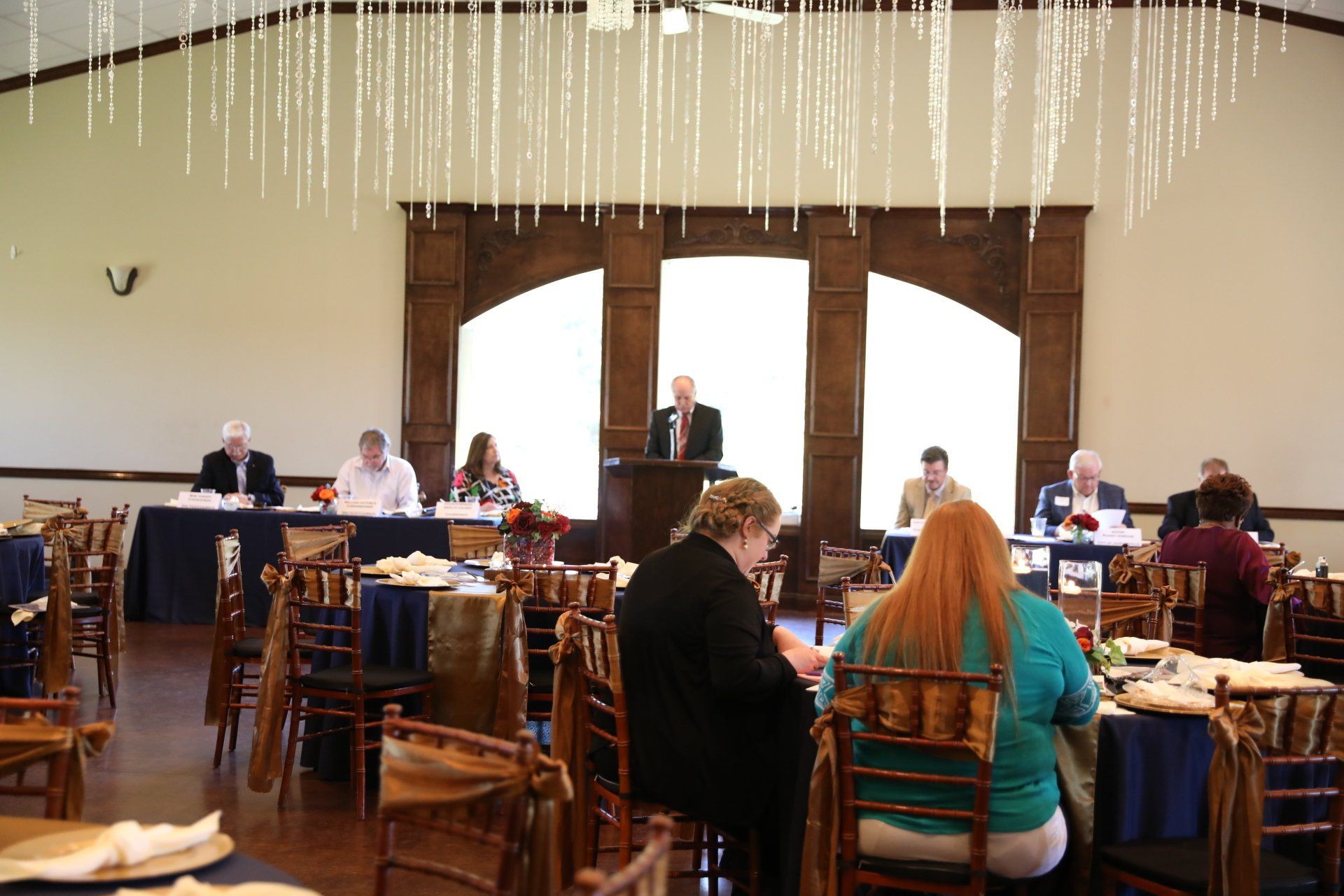 A group of people are sitting at tables in a large room.