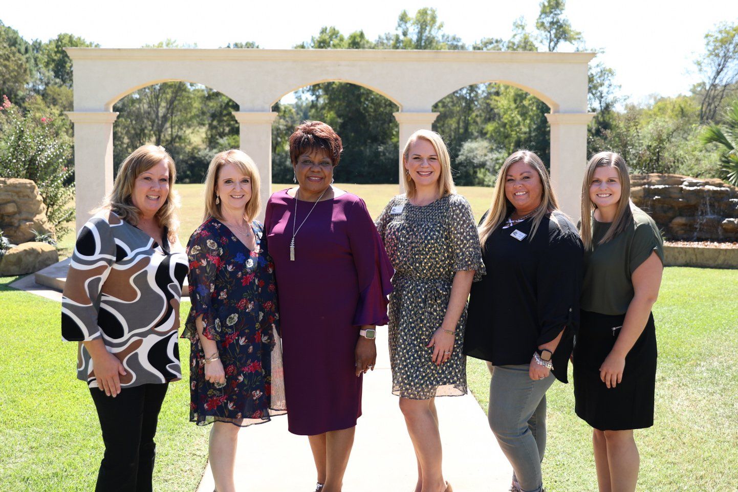 A group of women are posing for a picture in a park.