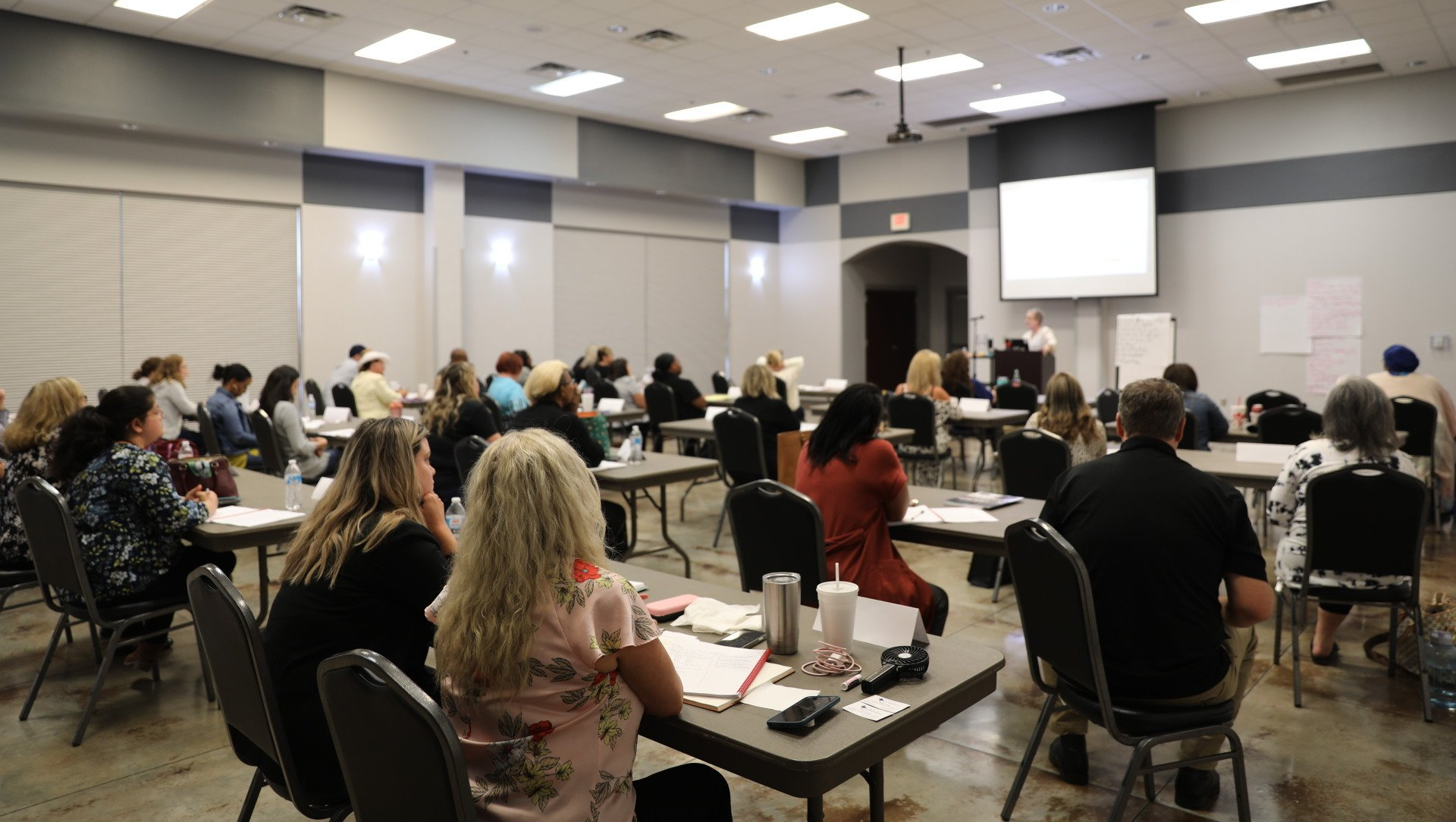 A large group of people are sitting at tables in a room.