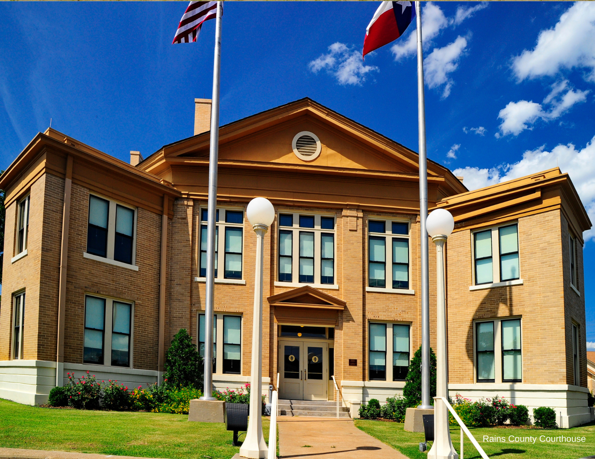 A large brick building with three flags in front of it