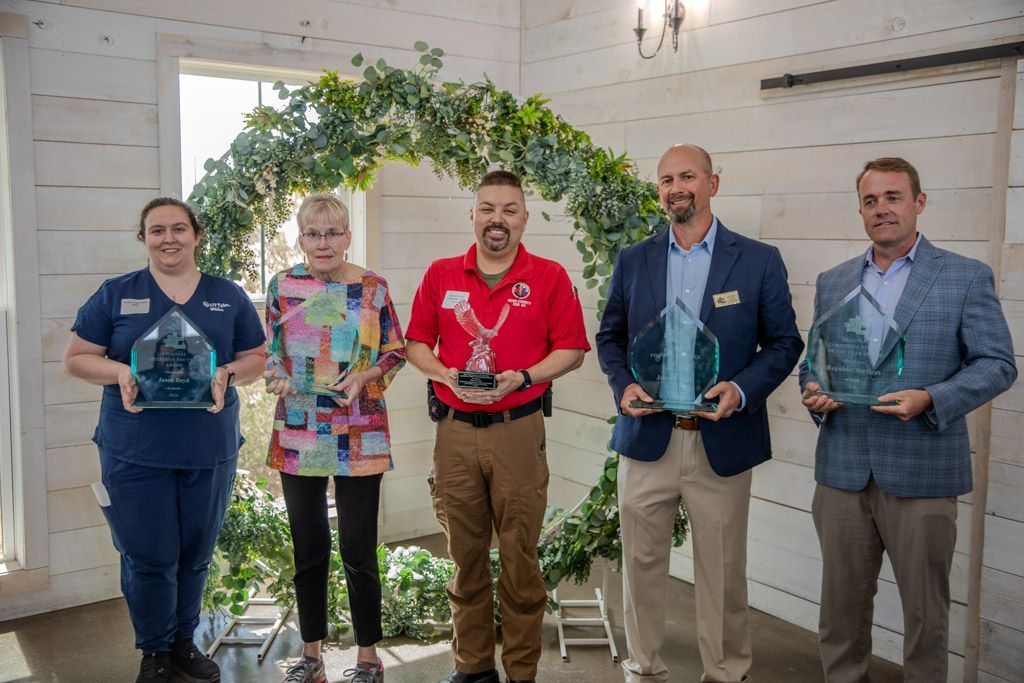 A group of people are standing next to each other holding awards.