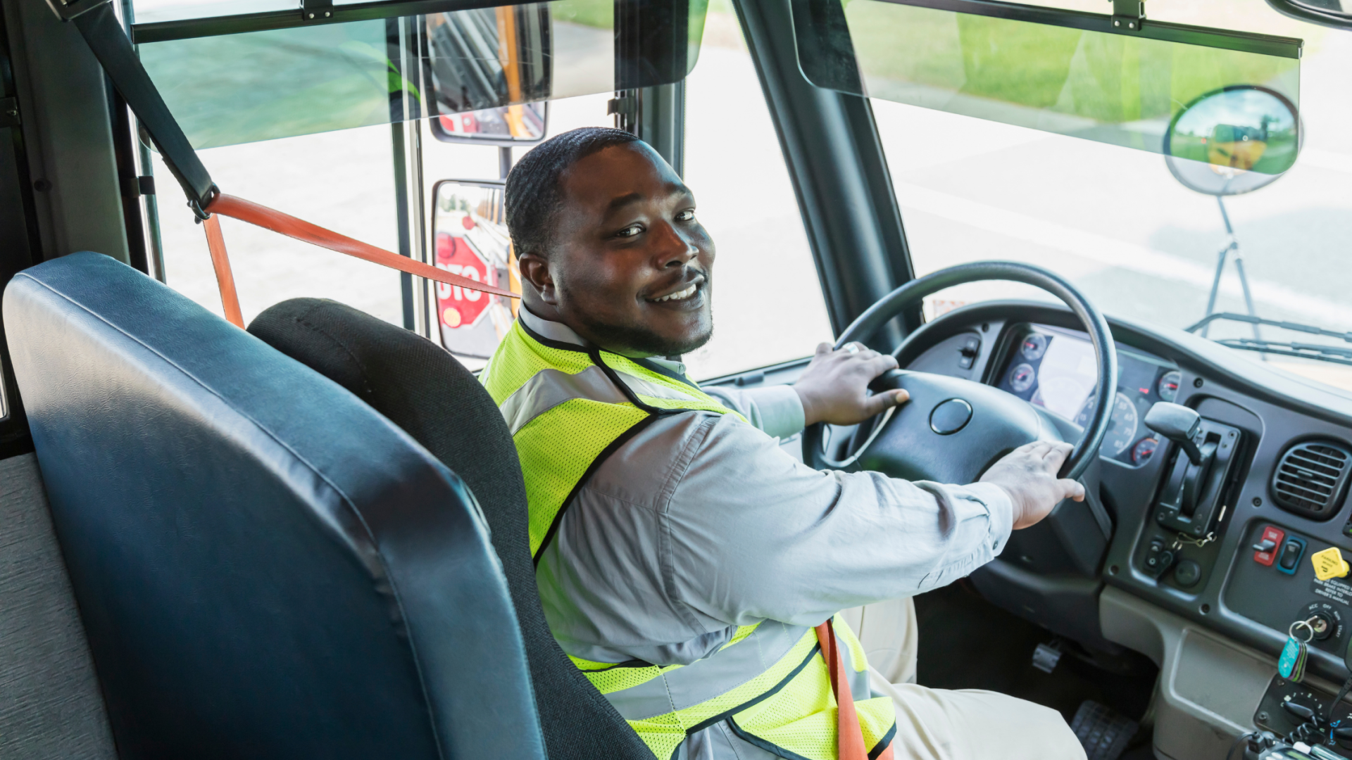 A man is sitting in the driver 's seat of a bus.