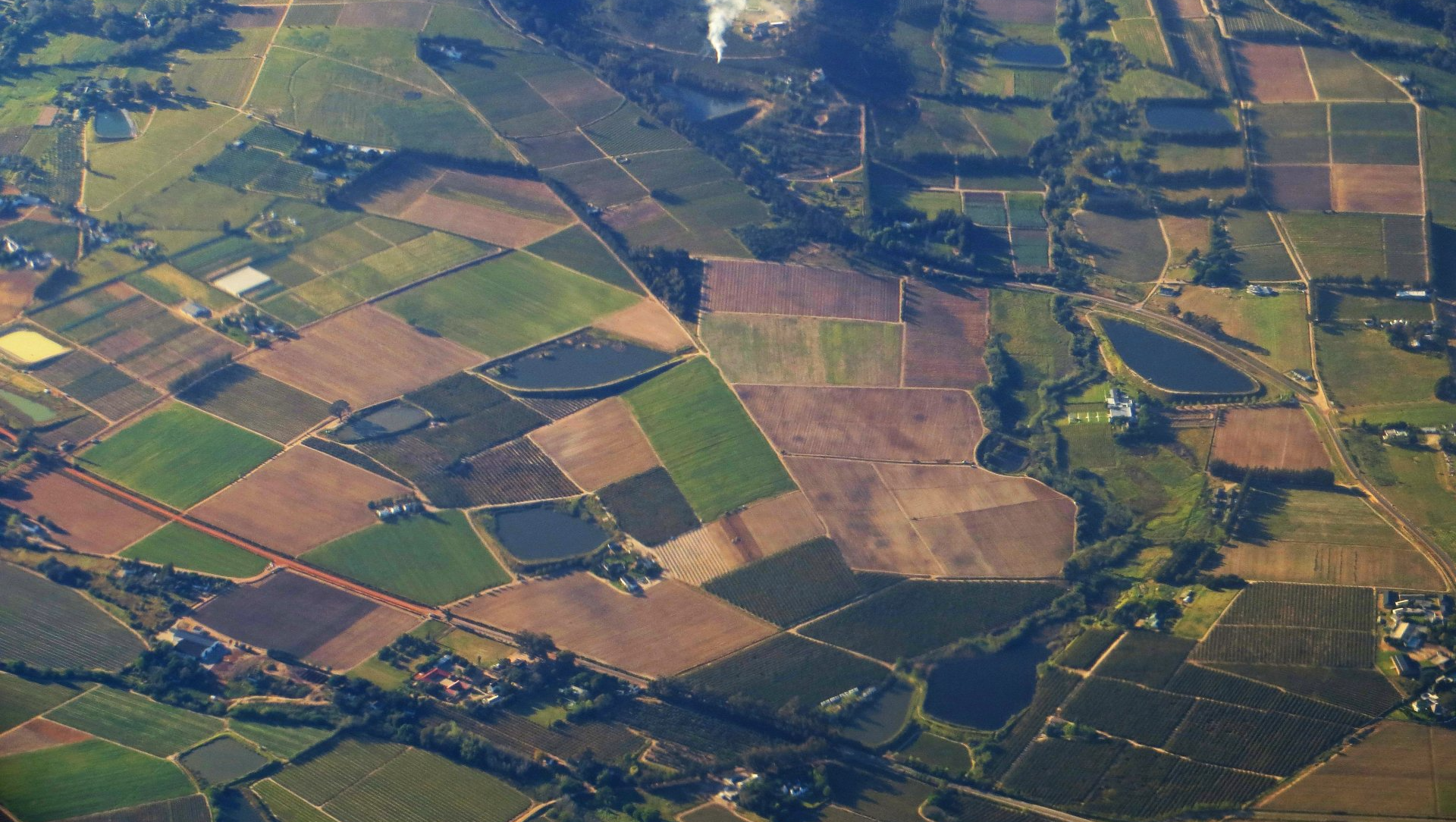 An aerial view of a lush green field with lots of fields and trees