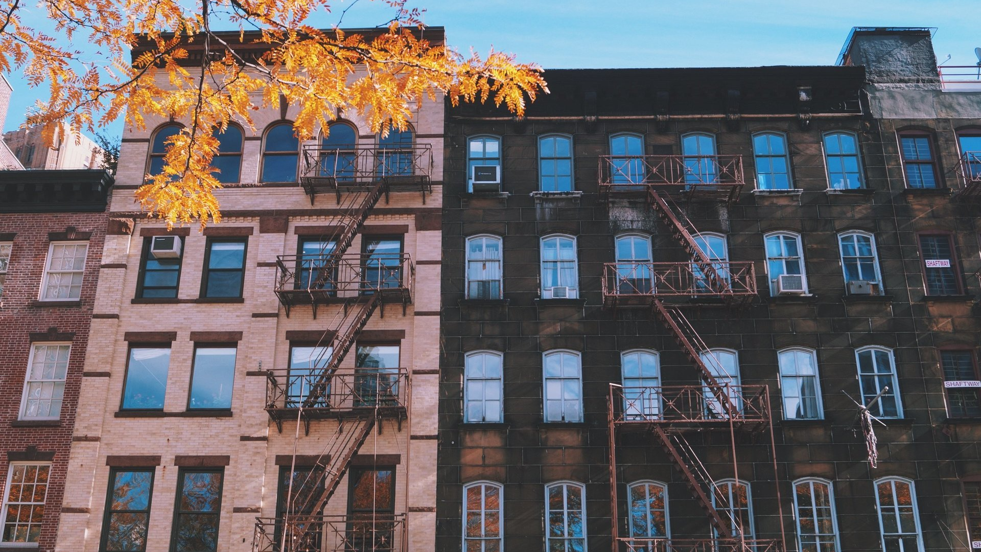 A fire escape is on the side of a building next to another building.