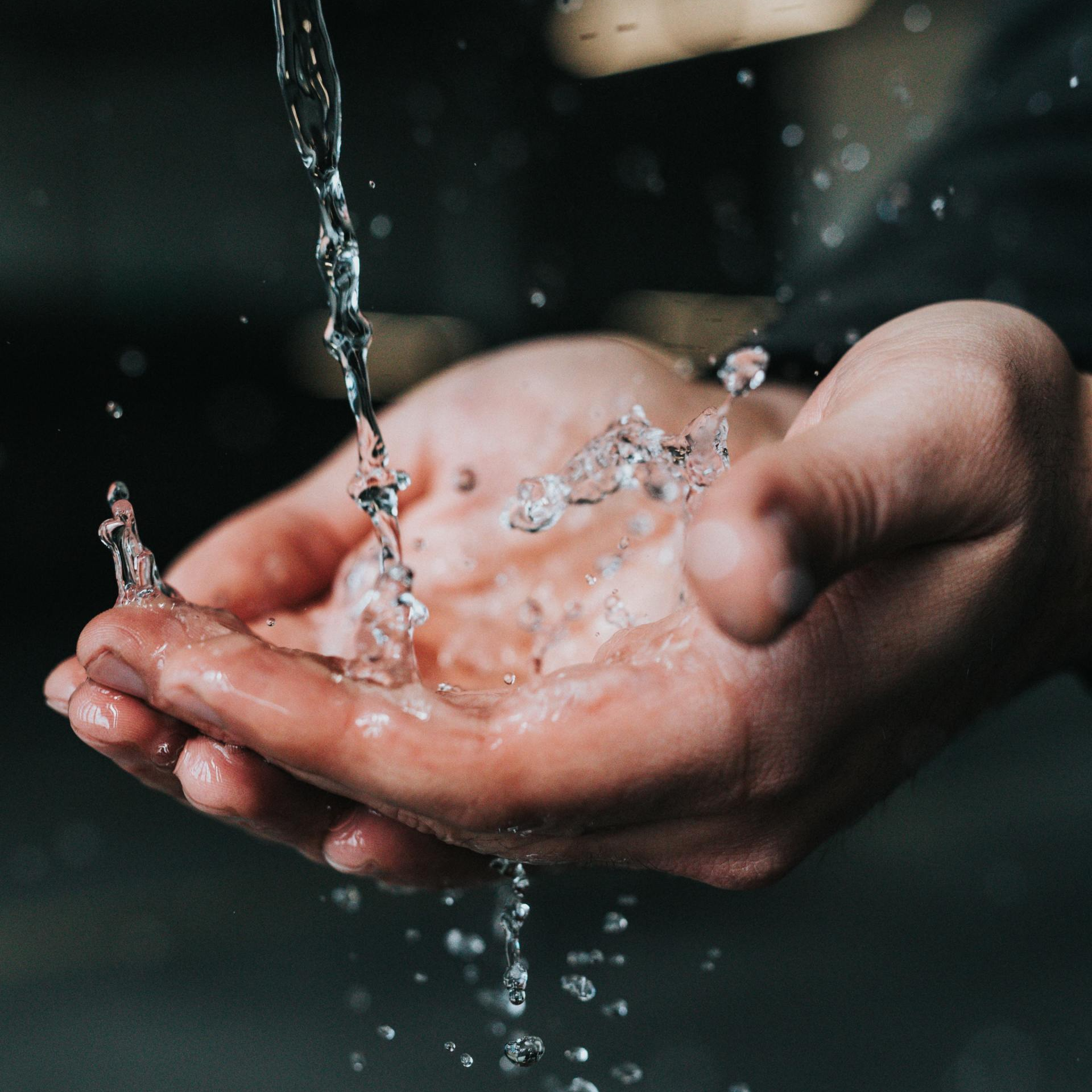 A close up of a person holding water in their hands