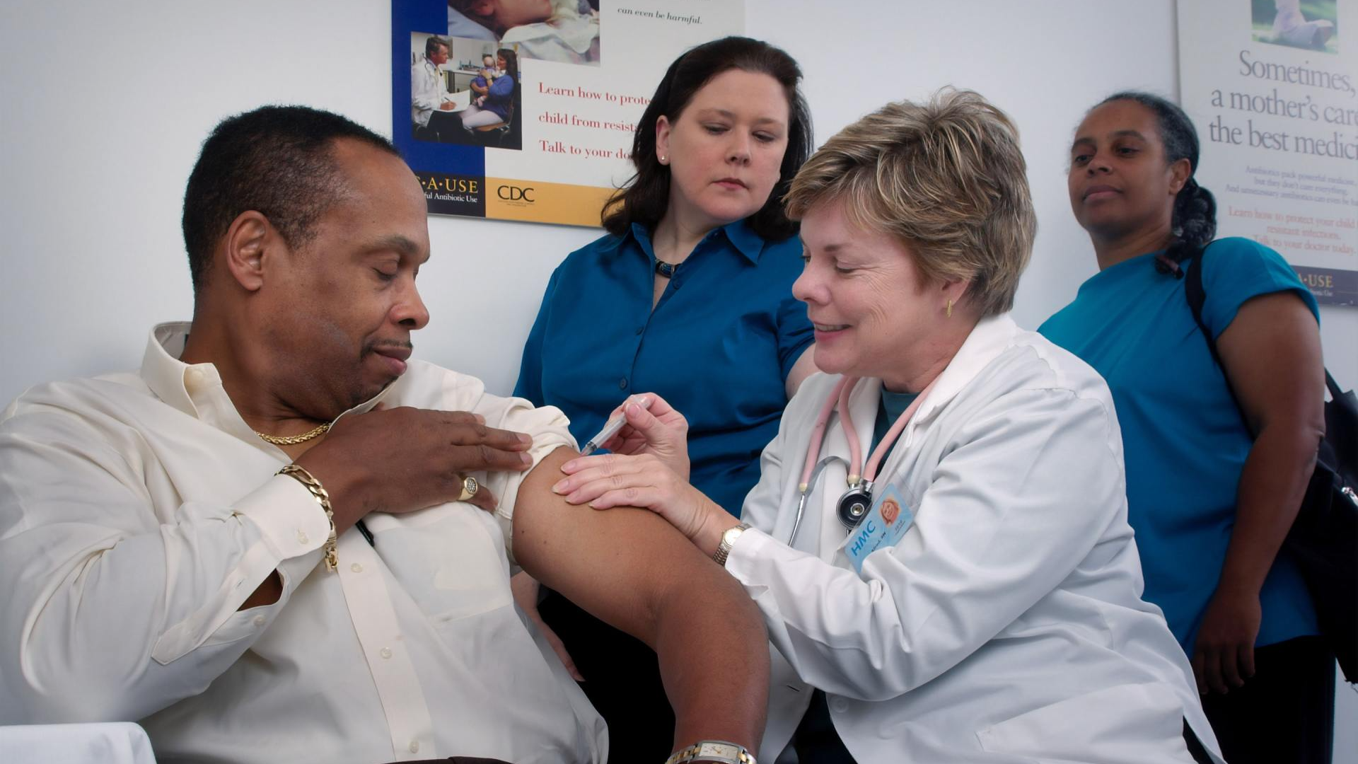 A doctor is giving a man an injection in his arm