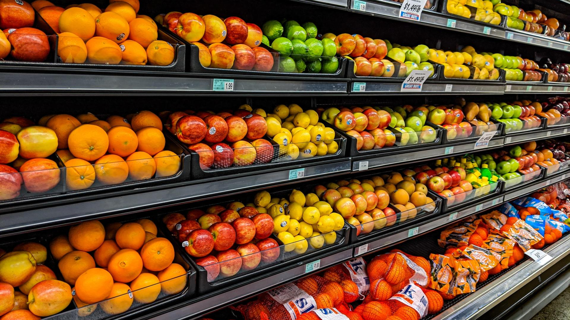 A grocery store aisle filled with lots of fruits and vegetables.