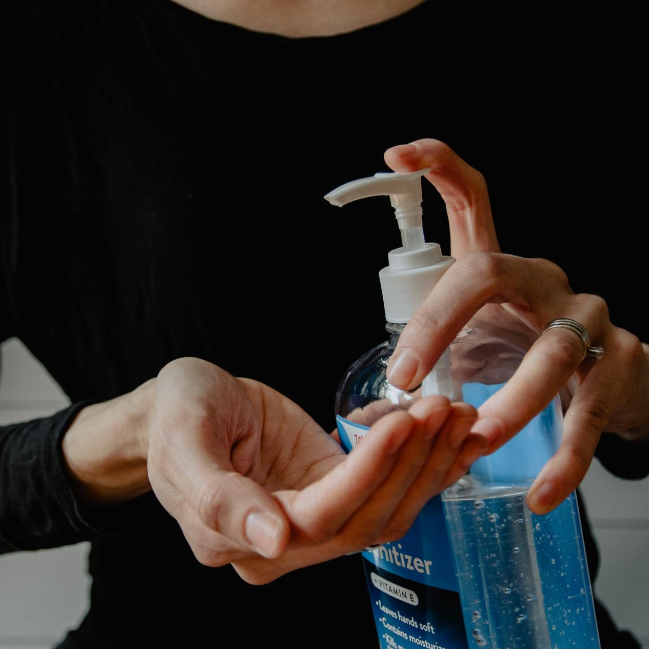 A woman is holding a bottle of hand sanitizer in her hands