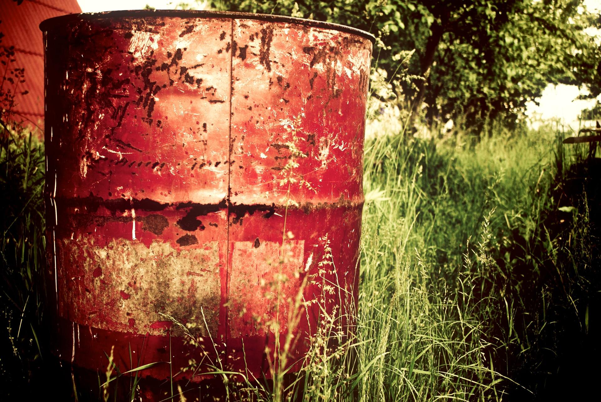 A rusty red barrel is sitting in the grass