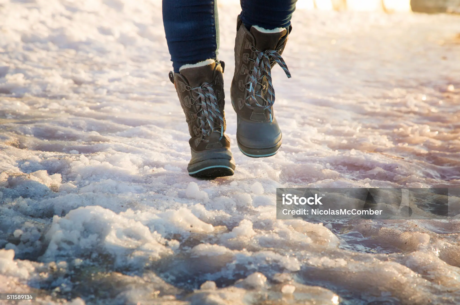 Person walking on an icy surface wearing winter boots with thick soles.