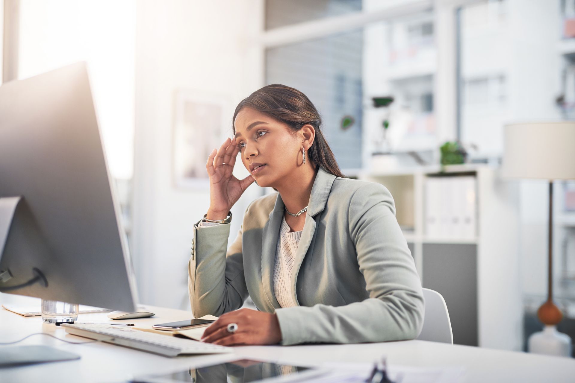 Concerned employee sitting at a desk, dealing with workplace issues.