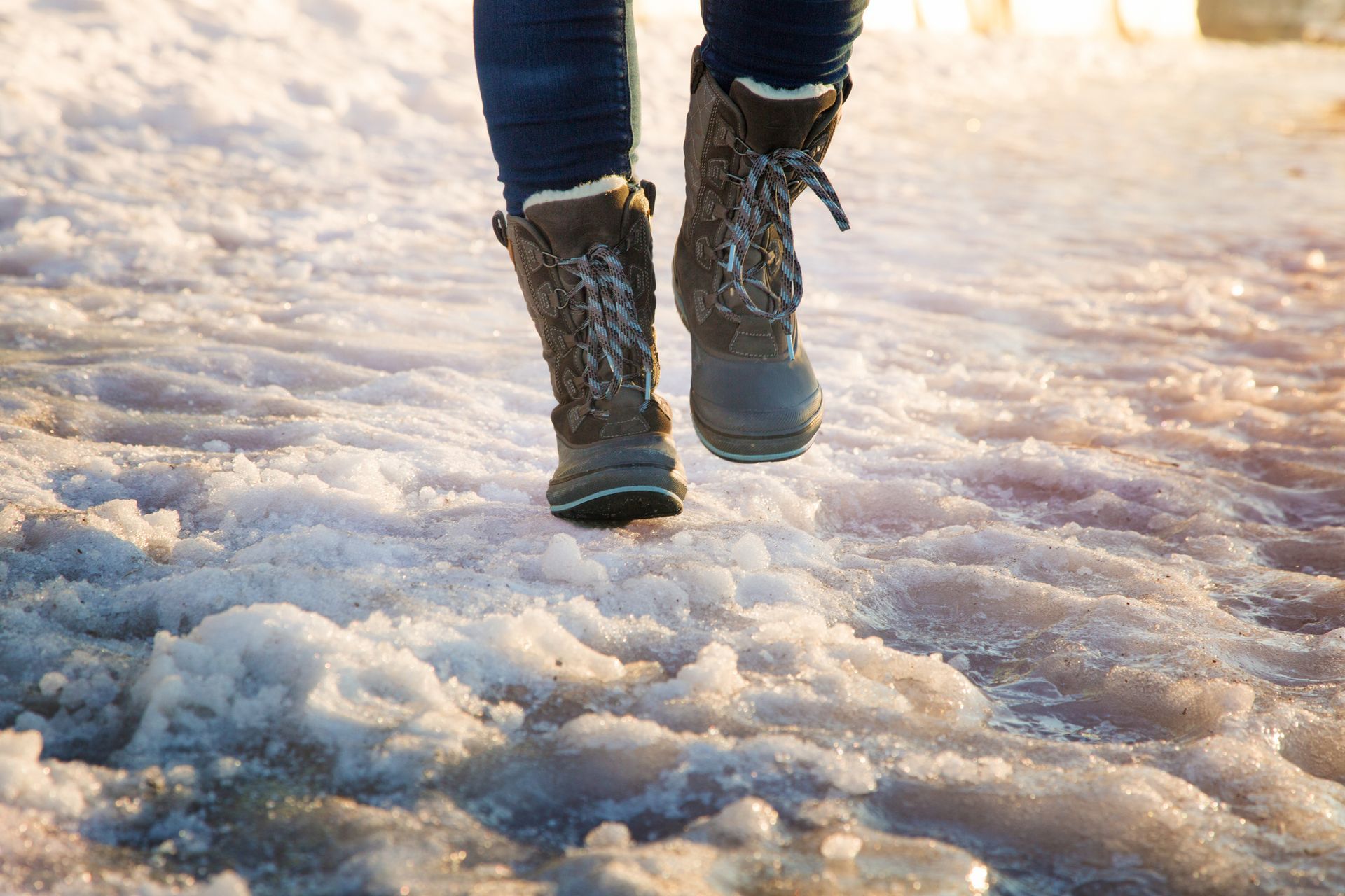 Person walking on an icy surface wearing winter boots with thick soles.