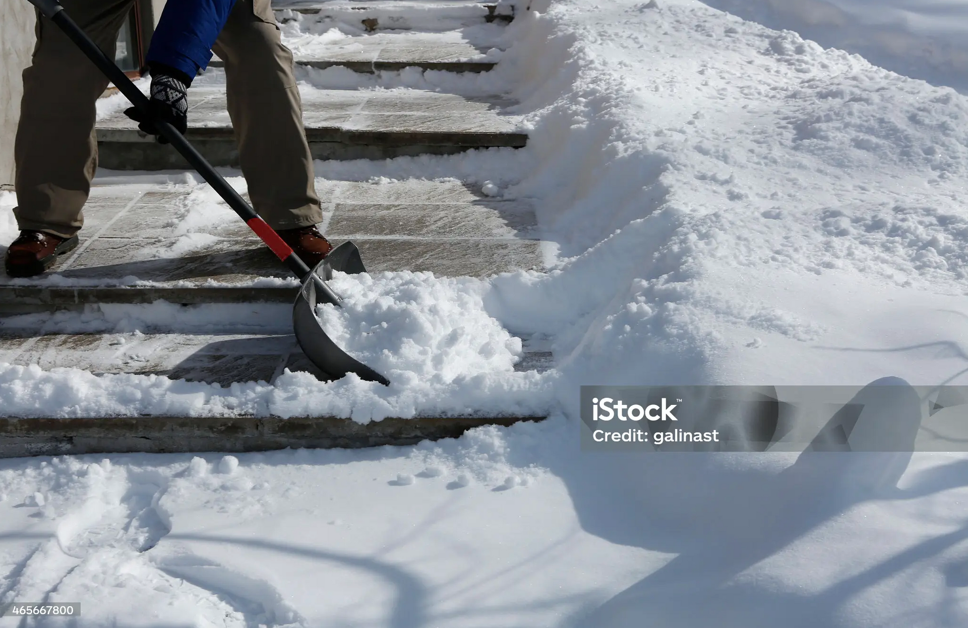 Person shoveling snow off outdoor steps to prevent slip and fall accidents.