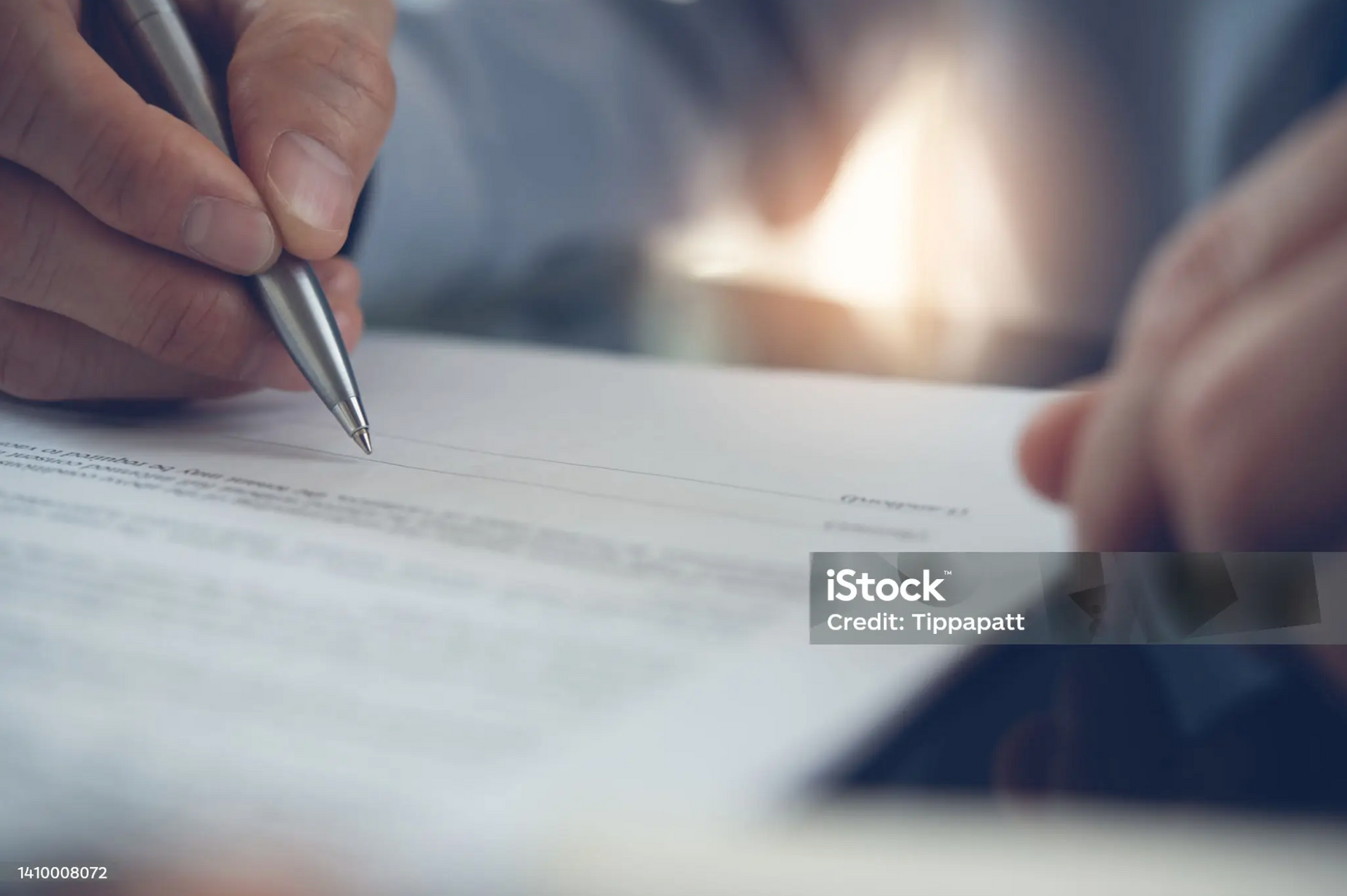 Close-up of a person signing an employment contract.